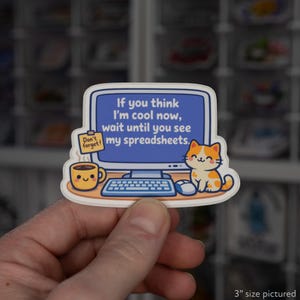 May include: A sticker featuring a computer monitor with the text "If you think I'm cool now, wait until you see my spreadsheets." A cute orange and white cat, a coffee cup, and a "Don't forget!" sticky note are also on the sticker.