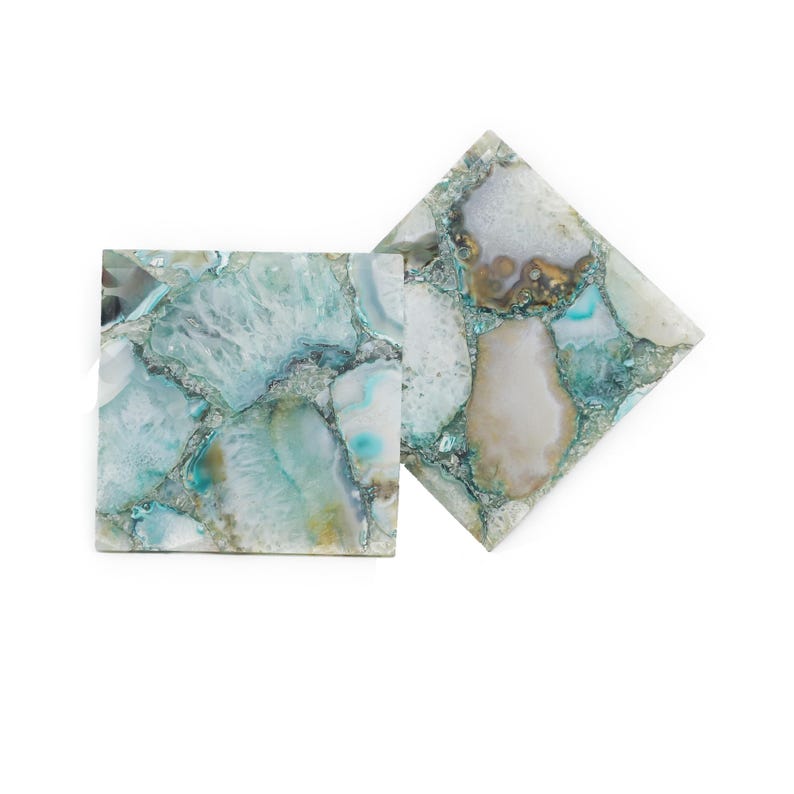 Puede incluir: Dos posavasos cuadrados hechos de rodajas de &aacute;gata pulida en tonos verde azulado, blanco y marr&oacute;n claro. La superficie presenta un mosaico de fragmentos de piedra natural con texturas cristalinas transl&uacute;cidas y vetas minerales visibles.