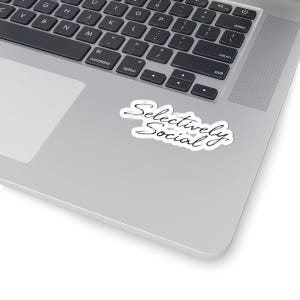 May include: A die-cut vinyl sticker featuring the black cursive text Selectively Social on a white background. The sticker has a thin white border and is placed on the silver metallic surface of a laptop keyboard area with black keys.