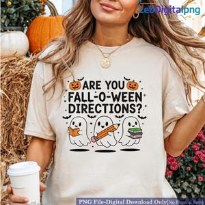 May include: Beige t-shirt with the text "ARE YOU FALL-O-WEEN DIRECTIONS?" and a graphic of three cartoon ghosts holding a book, pencil, and books. The design includes pumpkins and bats, perfect for Halloween.