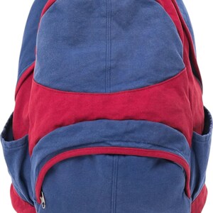 K&ouml;nnte beinhalten: Ein Rucksack aus Segeltuch mit einem Color-Block-Design in Dunkelblau und Dunkelrot. Der Rucksack verf&uuml;gt &uuml;ber ein gro&szlig;es Hauptfach, eine kleinere Fronttasche mit Rei&szlig;verschluss und geschwungener Klappe sowie zwei Seitentaschen aus strapazierf&auml;higem Stoff.