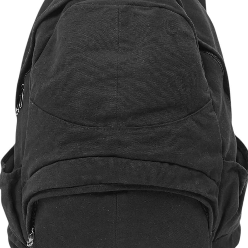 K&ouml;nnte beinhalten: Ein einfarbiger schwarzer Rucksack mit einem gro&szlig;en Hauptfach mit geschwungenem Rei&szlig;verschluss, einer vorderen Rei&szlig;verschlusstasche mit horizontaler Klappe und zwei Seitentaschen. Die Tasche besteht aus strapazierf&auml;higem Stoff mit sichtbaren N&auml;hten.