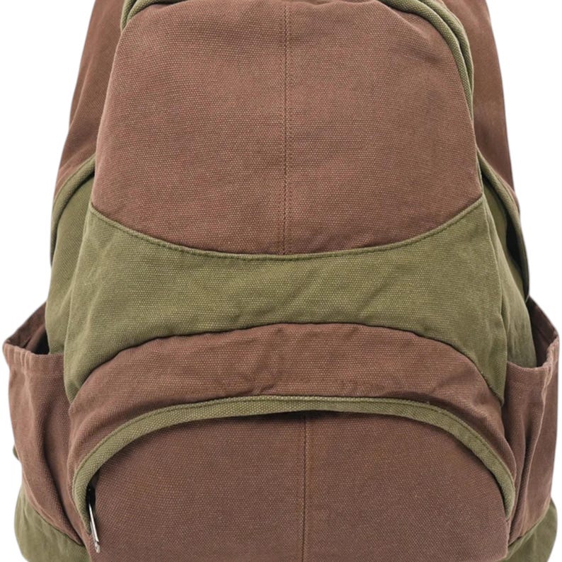 K&ouml;nnte beinhalten: Ein Rucksack aus Segeltuch mit einem farblich abgesetzten Design in Braun und Olivgr&uuml;n. Die Tasche verf&uuml;gt &uuml;ber ein gro&szlig;es Hauptfach, eine kleinere Rei&szlig;verschlusstasche auf der Vorderseite und zwei Seitentaschen aus strapazierf&auml;higem Stoff.
