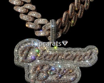 May include: A diamond-encrusted pendant necklace with the words "Diamond Boys" in a cursive font. The necklace has a thick, gold chain with a diamond-studded clasp. The pendant and chain sparkle against a black background.
