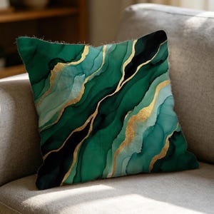 May include: A square throw pillow featuring an abstract marble pattern in shades of deep emerald green, forest green, and light mint, accented with flowing, organic veins of metallic gold that traverse the surface of the fabric.