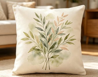 May include: A square throw pillow with an off-white base colour featuring a centred watercolour illustration of leafy branches in shades of sage green, olive, and soft peach, accented by subtle green watercolour washes in the background.