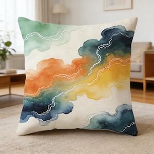 May include: A square throw pillow featuring an abstract watercolor design with flowing bands of sage green, deep navy blue, vibrant orange, and golden yellow. Thin, wavy white lines trace the edges of the color fields against a cream background.