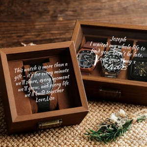 May include: Two wooden watch display boxes with glass lids. One box contains a black watch with a black band, and the other holds three watches. Text on the boxes reads: "This watch is more than a gift" and "I waited my whole life to find you."
