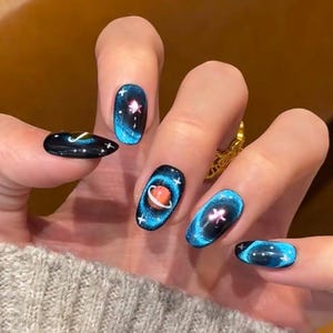 以下が含まれることがあります： 宇宙をテーマにしたデザインでペイントされた、長い楕円形の爪を持つ手。各爪は、渦巻く銀河効果、惑星、星を備えた濃い青色のベースを備えています。爪は青、オレンジ、白の色合いでアクセントが付けられています。