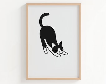 Peut inclure: Une impression d'art encadrée représentant une illustration minimaliste d'un chat noir qui s'étire. Le chat a des pattes blanches et une tache blanche sur le visage. L'œuvre est placée sur un fond blanc dans un cadre en bois brun clair.