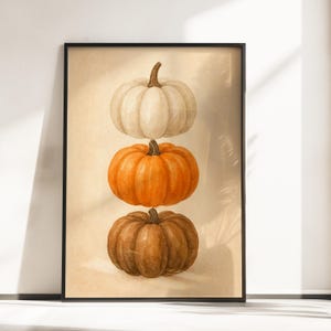 Puede incluir: Un estampado enmarcado con tres calabazas apiladas verticalmente. La calabaza superior es blanca, la del medio es naranja y la inferior es marrón. Las calabazas tienen superficies texturizadas y tallos verdes. El fondo es beige claro.