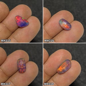 Könnte beinhalten: Vier polierte Opal-Edelsteine mit leuchtenden Farben wie Rot, Orange, Blau und Grün. Jeder Stein wird in einer Hand gehalten und mit einer eindeutigen Kennung versehen: MH315, MH316, MH317 und MH318. Die Opale haben eine glatte, reflektierende Oberfläche.