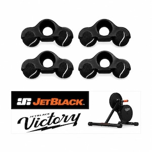 May include: Four black plastic bicycle trainer feet attachments, each featuring two integrated black tennis balls with white seams. Below, a black and white graphic displays the text JetBlack and Victory alongside a black indoor bike trainer.