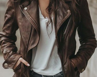 Puede incluir: Chaqueta de cuero marrón con cremallera asimétrica. La chaqueta tiene cuello con solapas, bolsillos y detalles plateados. La persona lleva una camiseta blanca y vaqueros azules.