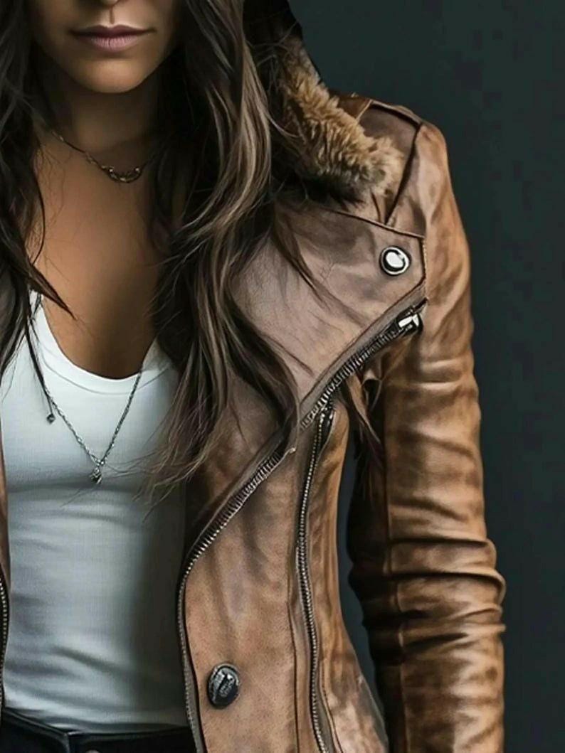 Puede incluir: Chaqueta de cuero marr&oacute;n con cuello de piel sint&eacute;tica y cremallera diagonal. La chaqueta tiene un bot&oacute;n en el hombro y una cremallera plateada. La modelo lleva una camiseta sin mangas blanca y un collar plateado.