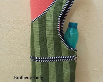 May include: Green striped yoga mat bag with a black and white striped trim and a teal water bottle in the side pocket. A rolled-up coral yoga mat is inside the bag. The text "Brothersartmfg" is printed on the bag.