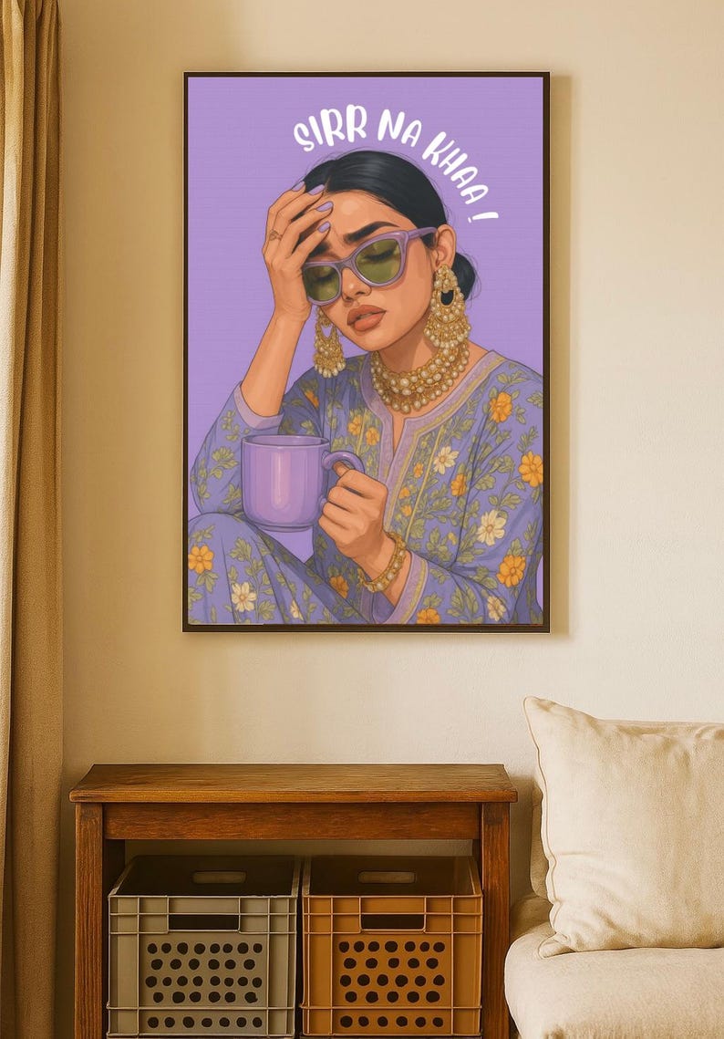May include: A framed art print featuring a woman in a blue floral patterned outfit, holding a purple mug. She wears sunglasses and gold jewelry. The text "SIRR NA KHAA!" is above her head.