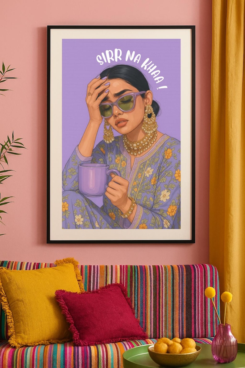 May include: Art print of a woman in a purple floral outfit, wearing sunglasses and gold jewelry, holding a purple mug. The artwork has the text "SIRR NA KHAA!" above the woman's head. The print is framed in a black frame.