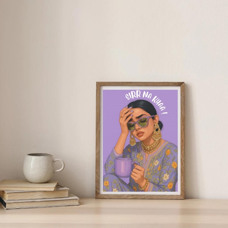 May include: A framed art print featuring a woman with sunglasses and gold jewelry, holding a purple mug. The print has the text "SIRR NA KHAA!" in white. The woman is wearing a purple floral patterned outfit.