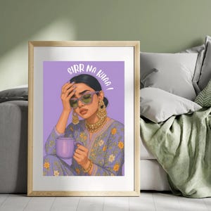 May include: A framed art print featuring a woman with sunglasses and gold jewelry, holding a purple mug. The artwork has the text "SIRR NA KHAA!" on a purple background. The woman is wearing a purple floral patterned outfit.