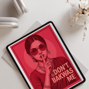 May include: Red and black tablet with a graphic of a woman wearing sunglasses and jewelry, with the text "DON'T BAKWAS ME". The tablet is on a white surface, with white headphones and a vase of dried flowers in the background.