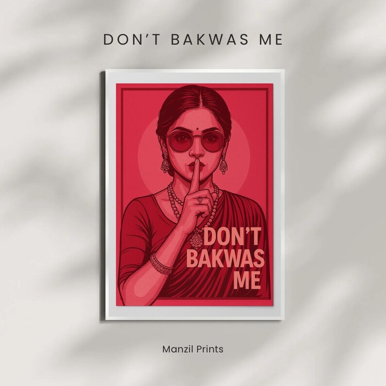 May include: A framed art print featuring a stylized illustration of a woman in a red sari, wearing sunglasses and holding a finger to her lips. The text "DON'T BAKWAS ME" is displayed above the image and below the image. The artist's name, "Manzil Prints", is at the bottom.