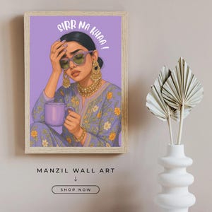 May include: A framed wall art print featuring a stylized illustration of a woman wearing sunglasses and holding a mug. The artwork has the text "SIRR NA KHAA!" and is labeled "MANZIL WALL ART". The woman is wearing a purple outfit with yellow floral details.