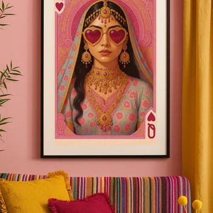 May include: A framed art print featuring a woman in traditional Indian attire, wearing heart-shaped sunglasses. The artwork is set against a pink and gold background, with the Queen of Hearts card suit symbols in the corners. The woman is adorned with gold jewelry.