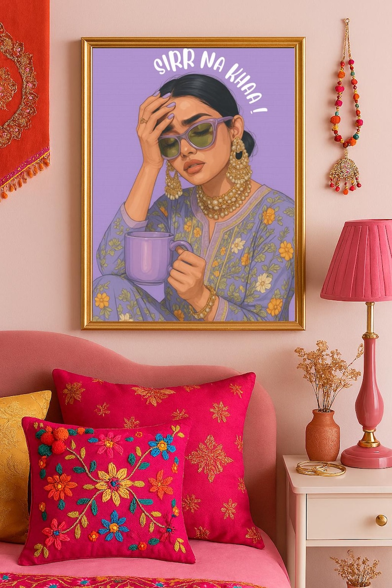 May include: A framed art print with the text "SIRR NA KHAA!". The artwork depicts a woman wearing sunglasses and holding a mug. The room features pink pillows, a lamp, and decorative items.