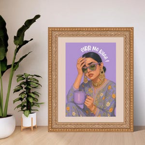 May include: Framed art print featuring a woman with sunglasses, holding a purple mug, and wearing a floral patterned outfit. The text "SIRR NA KHAA!" is displayed above the woman's head. The frame is gold.