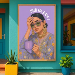 May include: A framed art print featuring a woman wearing sunglasses, gold jewelry, and a floral patterned outfit, holding a purple mug. The artwork has the text "SIRR NA KHAA!" in a stylized font against a purple background.