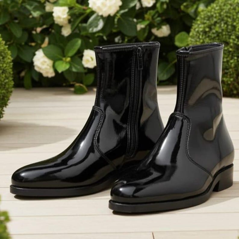 May include: A pair of black ankle boots with a high-gloss patent finish. These boots feature a sleek, pointed toe design, a low block heel, and a vertical zipper closure on the inner side of each boot, providing a polished and structured appearance.