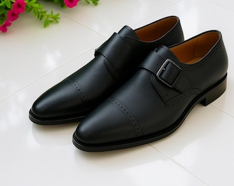 Elegantes zapatos de hombre de cuero negro hechos a mano con hebilla tipo monk strap, estilo clásico y formal.