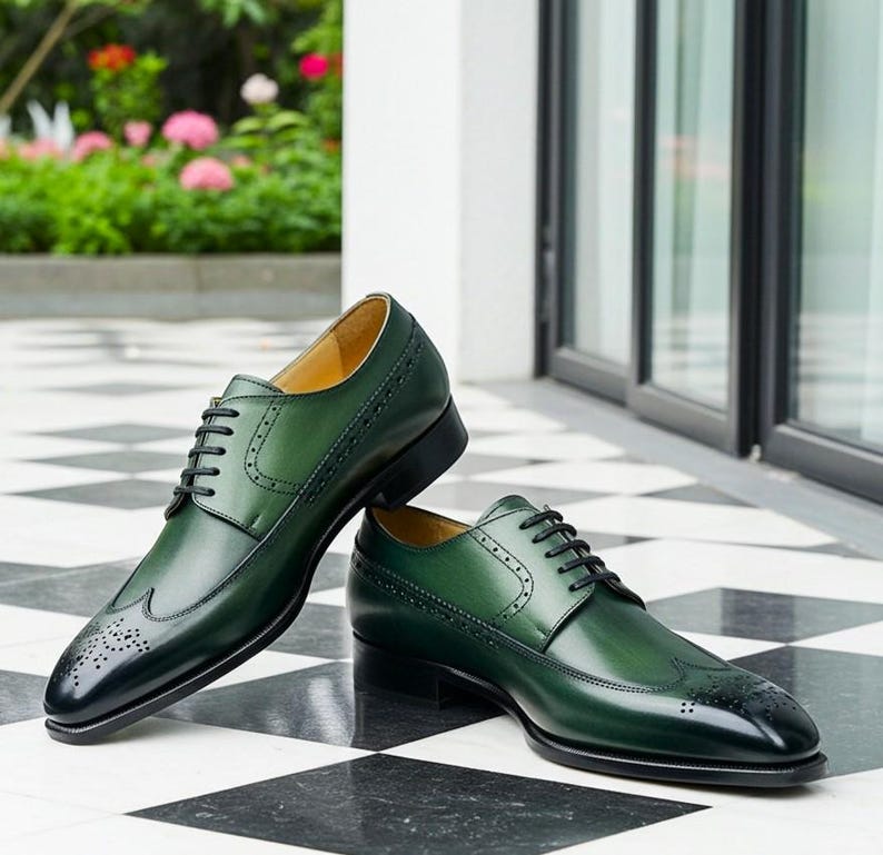 May include: A pair of green leather dress shoes with black laces. The shoes have a wingtip design with decorative perforations and a glossy finish. The shoes are displayed on a black and white checkered floor.