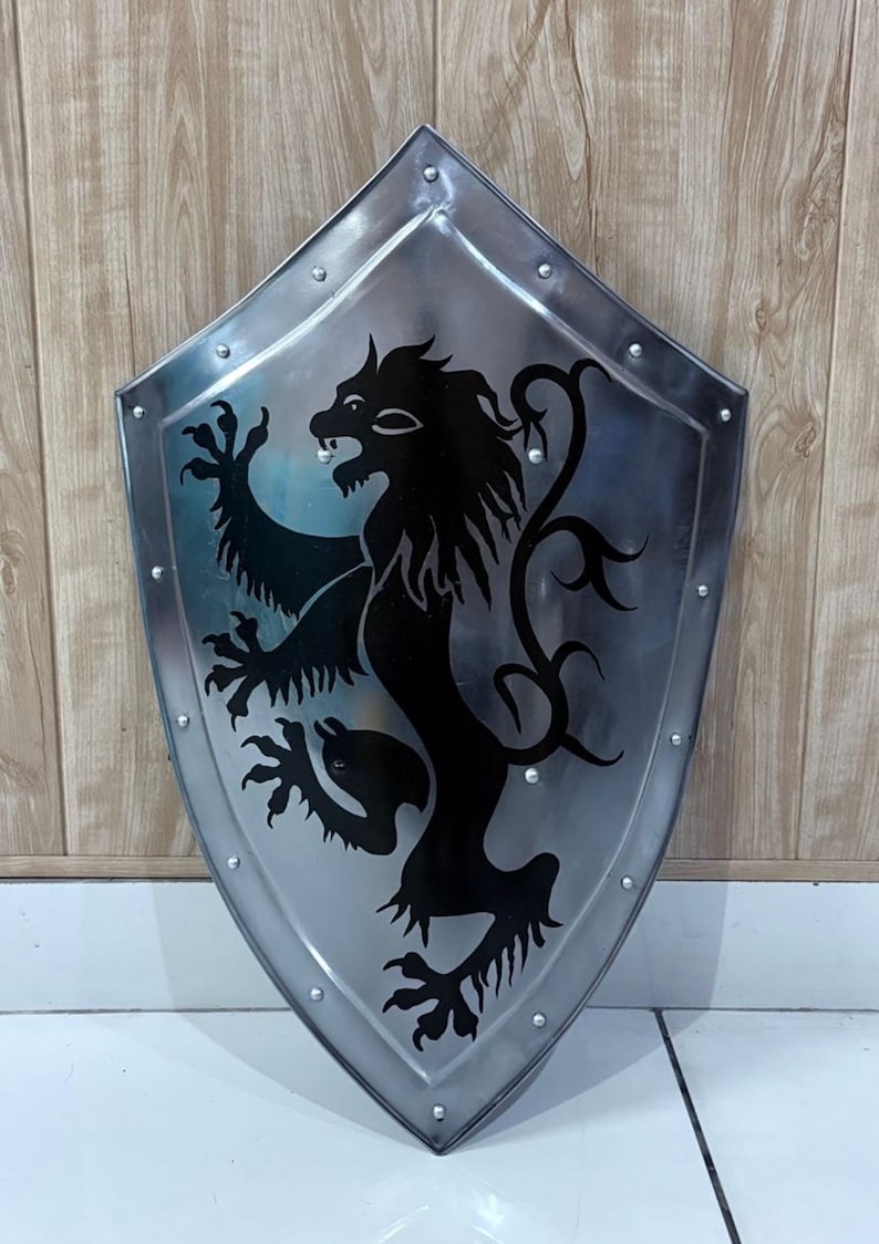 Pu&ograve; includere: Uno scudo color argento con un emblema di leone nero. Lo scudo ha una base a punta ed &egrave; bordato da rivetti. Il leone &egrave; in posa araldica, con le zampe anteriori sollevate. Lo scudo &egrave; probabilmente in metallo.