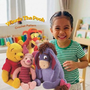 May include: A collection of handmade Winnie the Pooh crochet dolls, including Pooh Bear, Tigger, Piglet, and Eeyore. The dolls are in various colors, with the text "Winnie The Pooh Crochet Pattern" in the upper left corner. A smiling child is in the background.