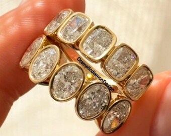 Anillo de eternidad con moissanita de talla cojín alargada, diamante de talla ovalada y oro amarillo de 18 quilates.