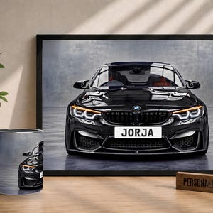 May include: A framed print and a ceramic mug featuring a black BMW M4 sports car with a front number plate that reads JORJA. The car is shown from the front with illuminated headlights and a dark grille. A wooden block displays the text PERSONALISED GIFT.