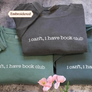 Peut inclure: Trois sweat-shirts à col rond en gris anthracite, vert sauge et bleu sarcelle foncé, chacun portant le texte brodé en blanc "i can't, i have book club" sur la poitrine. Une petite étiquette au-dessus affiche le mot "Embroidered".