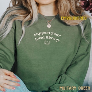 A person wearing a green sweatshirt with the text "Support your local library" printed on it.