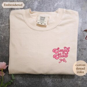 a white t - shirt with a pink design on it