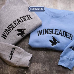 two sweatshirts with the same design, laid out on a surface.