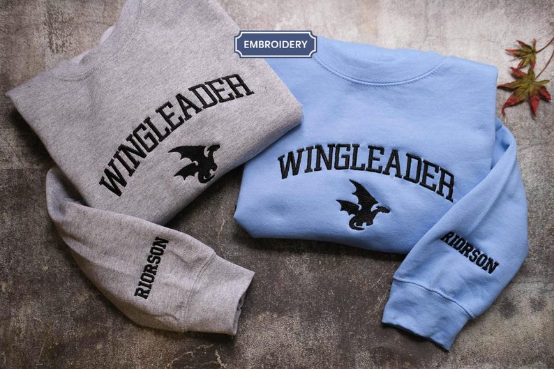 two sweatshirts with the same design, laid out on a surface.