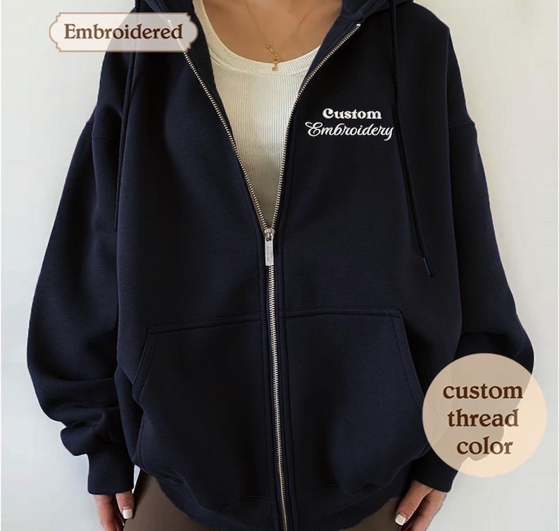 A close-up of a navy blue hooded sweatshirt with the text "Embroidered" and "Custom Embroidery" printed on it.