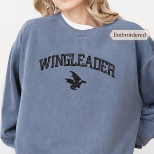 A person wearing a blue sweatshirt with the text "WINGLEADER" printed on it.