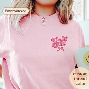 a woman wearing a pink tshirt holding a cup of coffee