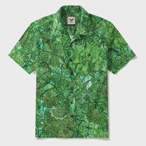 May include: Green short-sleeve button-down shirt with a vibrant, all-over floral pattern. The design features various shades of green, creating a stained-glass effect. The shirt has a classic collar and button closure, perfect for casual wear.