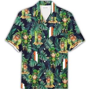 Puede incluir: Una camisa hawaiana de manga corta con un fondo azul oscuro, con un patrón repetido de hojas de palma verdes, duendes, tréboles y tablas de surf. La camisa tiene un cuello blanco y una franja vertical de la bandera irlandesa en la parte delantera.
