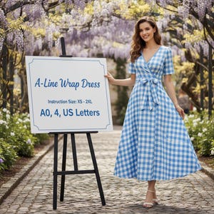 May include: A-line wrap dress in a blue and white gingham pattern. The dress features a V-neck, short sleeves, and a tie waist. The sign next to the dress reads "A-Line Wrap Dress" and "Instruction Size: XS - 2XL".