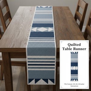 Peut inclure: Chemin de table matelassé bleu et blanc avec un motif géométrique, présenté sur une table en bois. Le chemin de table présente des rayures et des losanges. Le texte "Quilted Table Runner" est visible.
